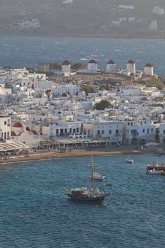 panoramic view of the Mykonos town harbor with famous windmills from the above hills on a sunny summer day, Mykonos, Cyclades, Greece 