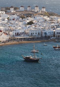 panoramic view of the Mykonos town harbor with famous windmills from the above hills on a sunny summer day, Mykonos, Cyclades, Greece 