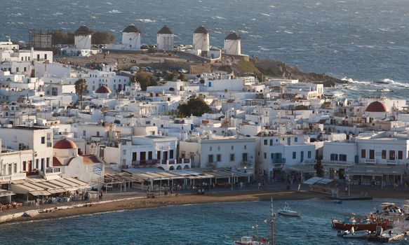 panoramic view of the Mykonos town harbor with famous windmills from the above hills on a sunny summer day, Mykonos, Cyclades, Greece 