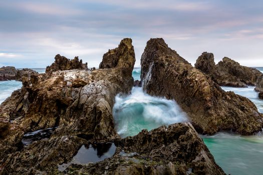 Ocean waves force their way through the gap in these dramatic jagged rocks 