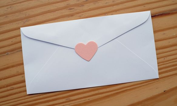 Valentine's day love letter envelope with hearts on wooden background. copy space