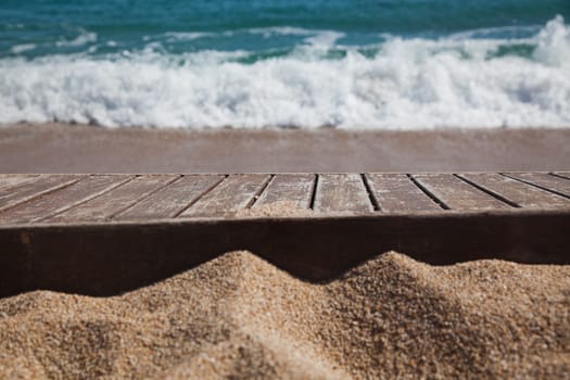 wooden plank in sand and blue sea in the background