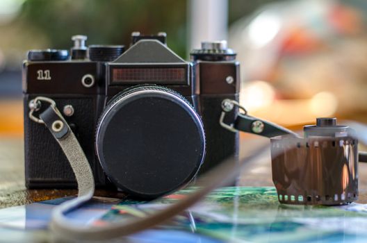 Old photo film roll and retro camera on desk.