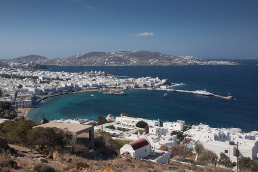 panoramic view of the Mykonos town harbor with famous windmills from the above hills on a sunny summer day, Mykonos, Cyclades, Greece 