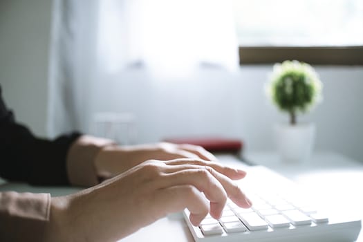 Woman working by using a laptop computer on wooden table. Hands typing on a keyboard.