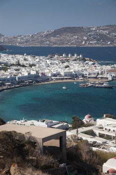panoramic view of the Mykonos town harbor with famous windmills from the above hills on a sunny summer day, Mykonos, Cyclades, Greece 