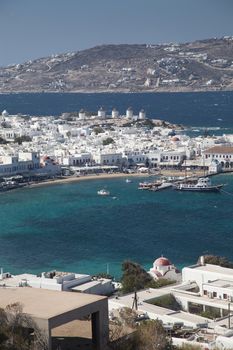 panoramic view of the Mykonos town harbor with famous windmills from the above hills on a sunny summer day, Mykonos, Cyclades, Greece 