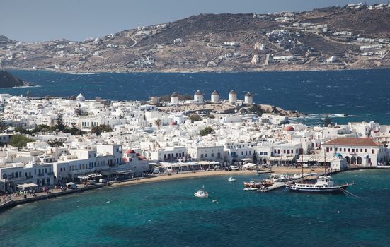 panoramic view of the Mykonos town harbor with famous windmills from the above hills on a sunny summer day, Mykonos, Cyclades, Greece 