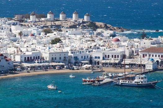 panoramic view of the Mykonos town harbor with famous windmills from the above hills on a sunny summer day, Mykonos, Cyclades, Greece 