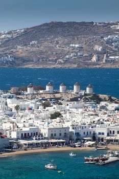panoramic view of the Mykonos town harbor with famous windmills from the above hills on a sunny summer day, Mykonos, Cyclades, Greece 
