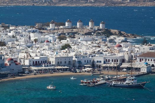 panoramic view of the Mykonos town harbor with famous windmills from the above hills on a sunny summer day, Mykonos, Cyclades, Greece 