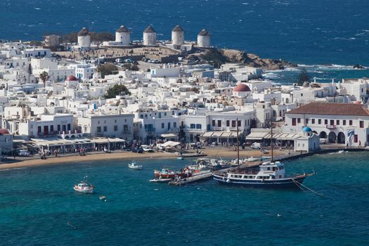 panoramic view of the Mykonos town harbor with famous windmills from the above hills on a sunny summer day, Mykonos, Cyclades, Greece 
