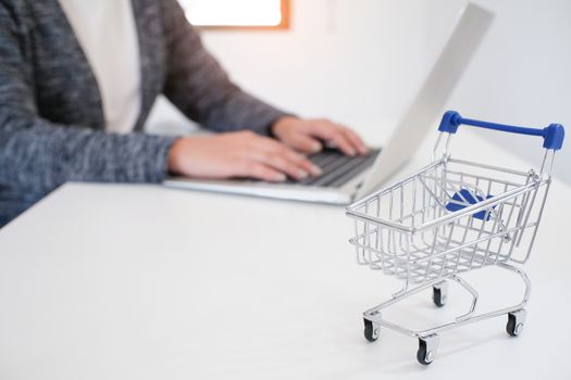 Woman and Small shopping cart with Laptop for Internet online shopping concept.