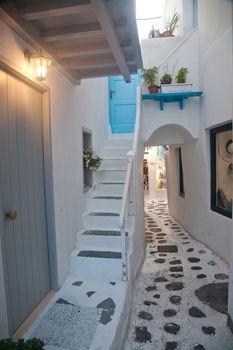 traditional narrow street in Mykonos with blue doors and white walls