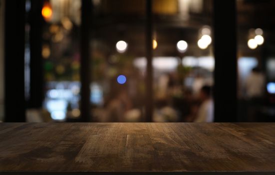 Empty dark wooden table in front of abstract blurred bokeh background of restaurant . can be used for display or montage your products.Mock up for space