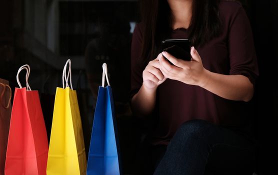 Asian girls holding sale shopping bags. consumerism lifestyle concept in the shopping mall hands holding cell telephone blank copy space screen 