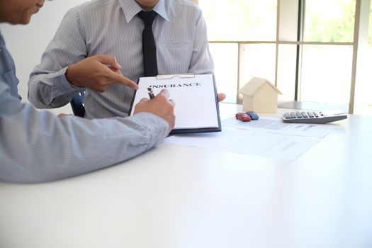 Sales manager giving advice application form document, considering mortgage loan offer for car and house insurance