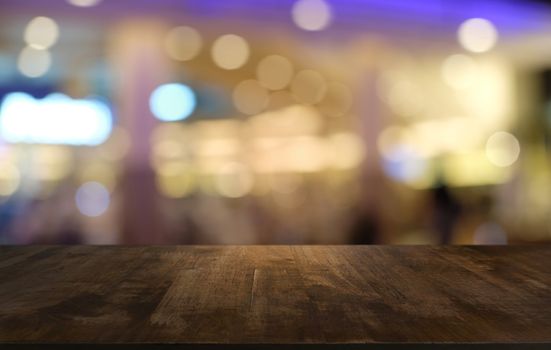 Empty dark wooden table in front of abstract blurred bokeh background of restaurant . can be used for display or montage your products.Mock up for space