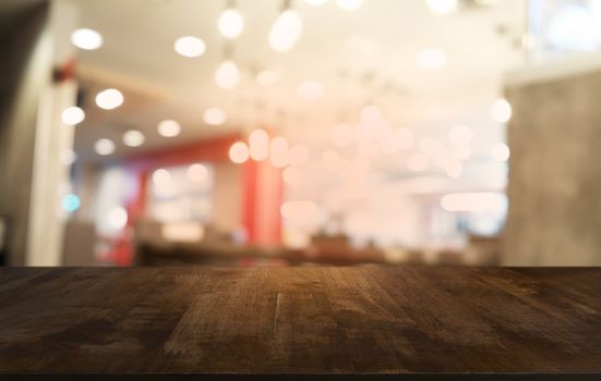 Empty dark wooden table in front of abstract blurred bokeh background of restaurant . can be used for display or montage your products.Mock up for space