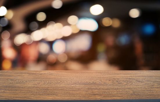 Empty dark wooden table in front of abstract blurred bokeh background of restaurant . can be used for display or montage your products.Mock up for space