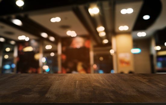 Empty dark wooden table in front of abstract blurred bokeh background of restaurant . can be used for display or montage your products.Mock up for space