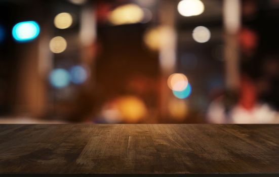 Empty dark wooden table in front of abstract blurred bokeh background of restaurant . can be used for display or montage your products.Mock up for space