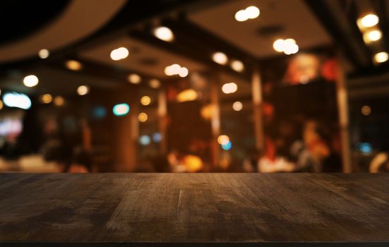 Empty dark wooden table in front of abstract blurred bokeh background of restaurant . can be used for display or montage your products.Mock up for space