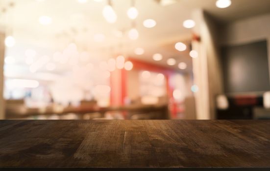 Empty dark wooden table in front of abstract blurred bokeh background of restaurant . can be used for display or montage your products.Mock up for space