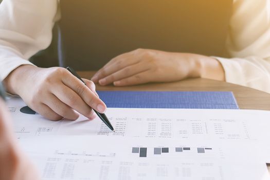 Businesswoman analyzing investment charts and pressing calculator buttons over documents. Accounting Concept