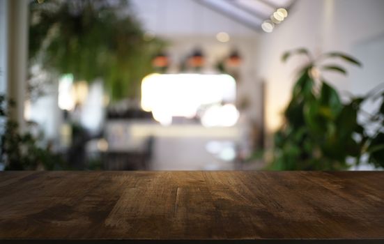 Empty dark wooden table in front of abstract blurred bokeh background of restaurant . can be used for display or montage your products.Mock up for space