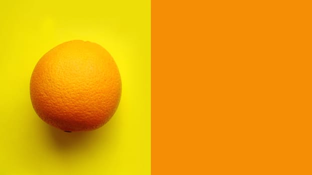 Whole orange fruit, top view. Isolated on yellow background isolated close up macro top view