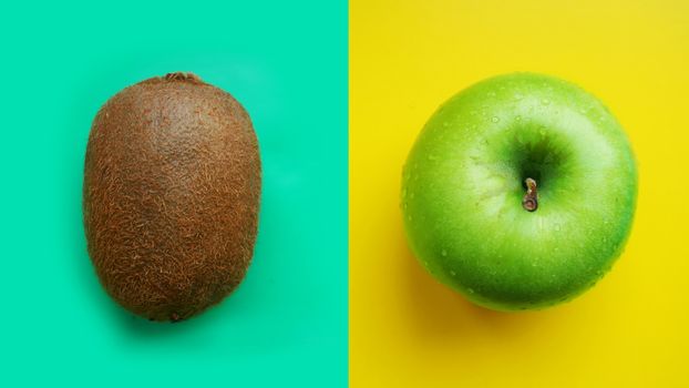 Green apple in water drops and kiwi on yellow and blue modern color background isolated close up macro top view