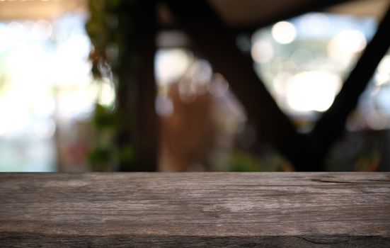 Empty dark wooden table in front of abstract blurred bokeh background of restaurant . can be used for display or montage your products.Mock up for space