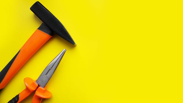 Tools worker, hammer, pliers on bright yellow background, top view. Repair tools