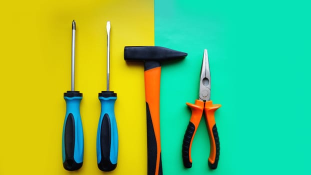 Tools worker, hammer, screwdrivers, pliers on bright yellow and blue background, top view. Repair tools