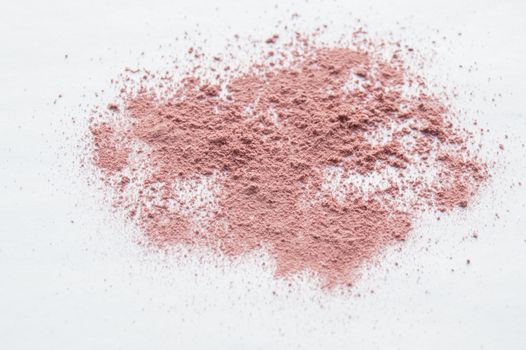 Scattered beige powder, Crumbles natural makeup powder on white background.