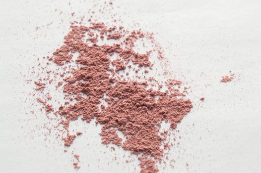 Scattered beige powder, Crumbles natural makeup powder on white background.