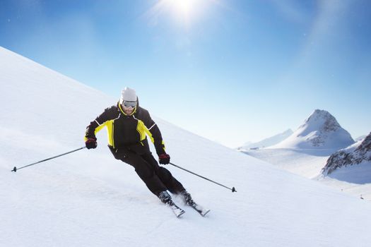 Alpine skier on piste running downhill in beautiful Alpine landscape. Blue sky on background. Free copy space for text