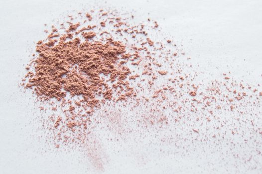 Scattered beige powder, Crumbles natural makeup powder on white background.