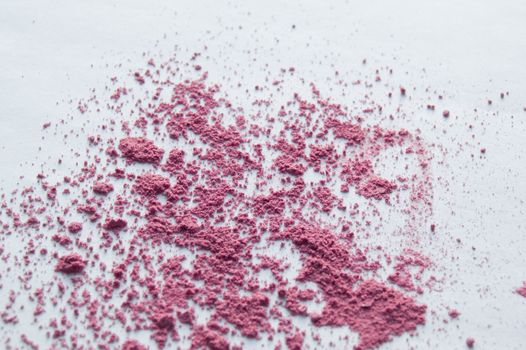 Pink blush scattered on white background, makeup background.