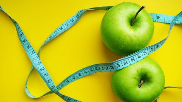Two Green apples with measurements isolated on a yellow background. fitness food