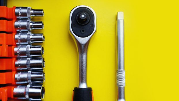 Wrench head bits for the screwdriver and other tools on bright yellow background, top view