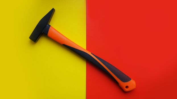 Hammer tool isolated on yellow and red background with copy space. Construction concept background.