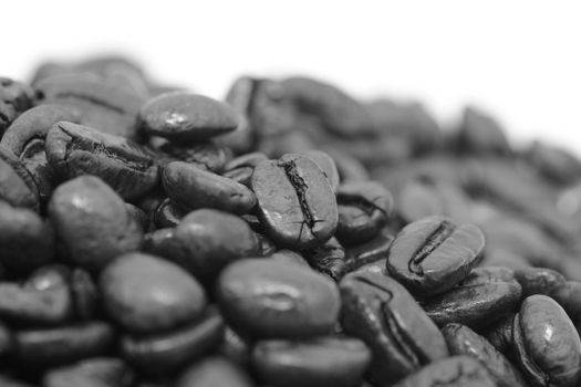 Macro of a pile of roasted coffee beans, on a white background - monochrome processing