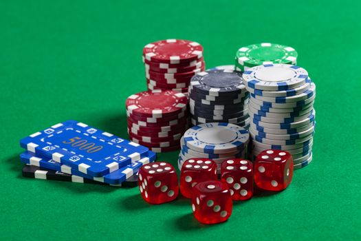 Pile of Casino Chips and Red Dice on Green Poker Table