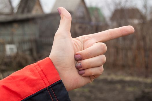 Woman hand making the sign of the index finger showing direction outdoors.