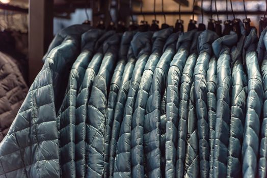 Close-up winter down on clothes rack at American outdoor clothing shop. Insulated fashionable jacket with zip pocket.