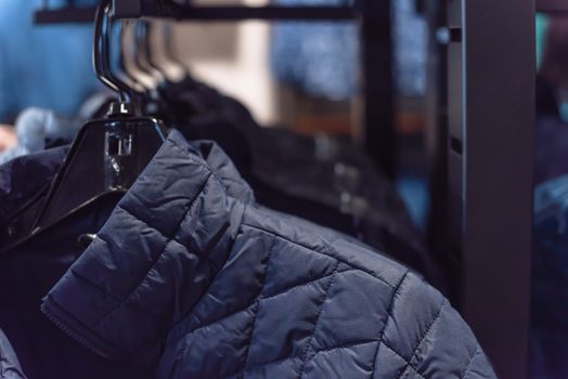 Close-up winter down on clothes rack at American outdoor clothing shop. Insulated fashionable jacket with zip pocket.