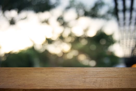 image of wooden table in front of abstract blurred background of outdoor garden lights. can be used for display or montage your products.Mock up for display of product