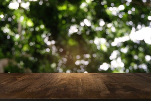 Image of dark wooden table in front of abstract blurred background of outdoor garden lights. can be used for display or montage your products.Mock up for display of product.